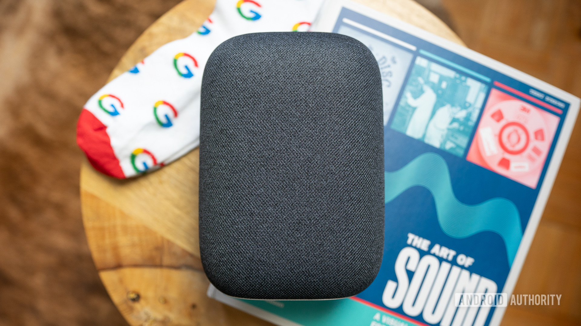 Google Nest Audio drivers Google Nest Audio on top of coffeetable with a book and pair of Google socks