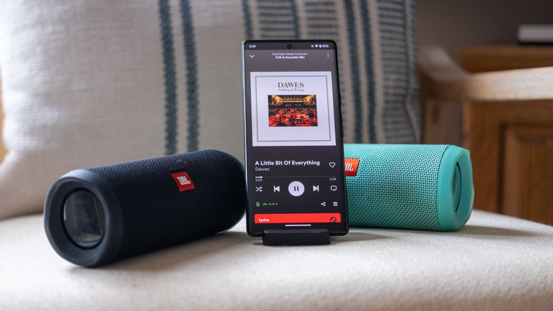 jbl connect spotify Two JBL Connect speakers, one blue, one black, either side of a phone playing music from the Spotify app.